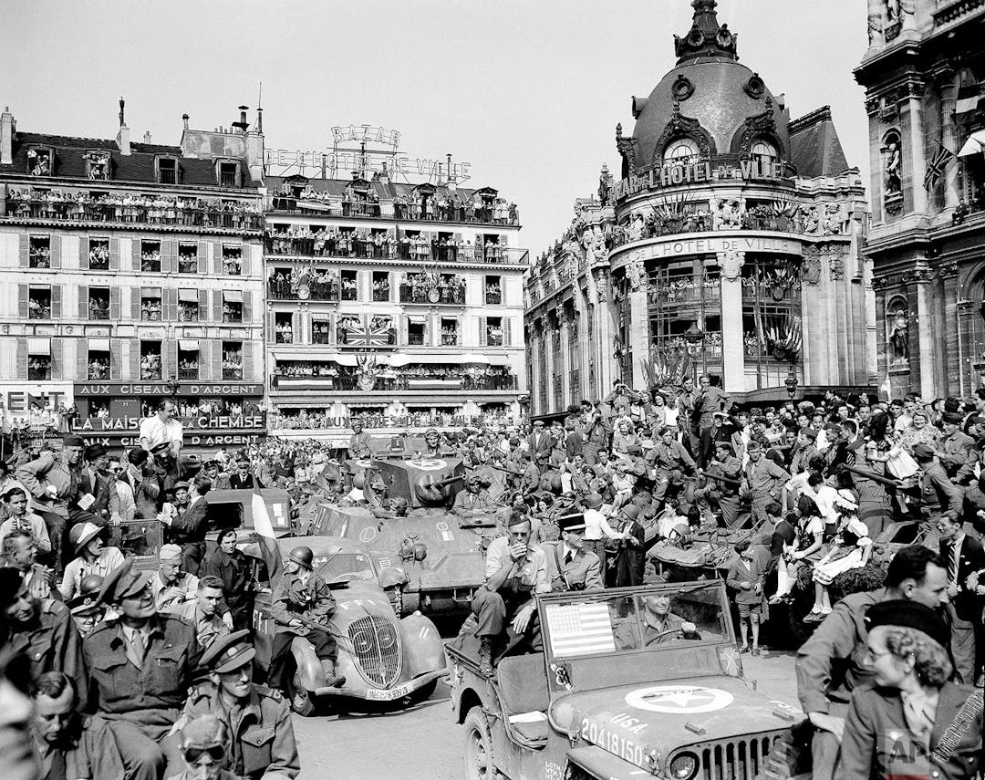 Mii de parizieni blochează Place de l’Hotel de Ville pentru a urmări marea paradă a generalului Charles de Gaulle.